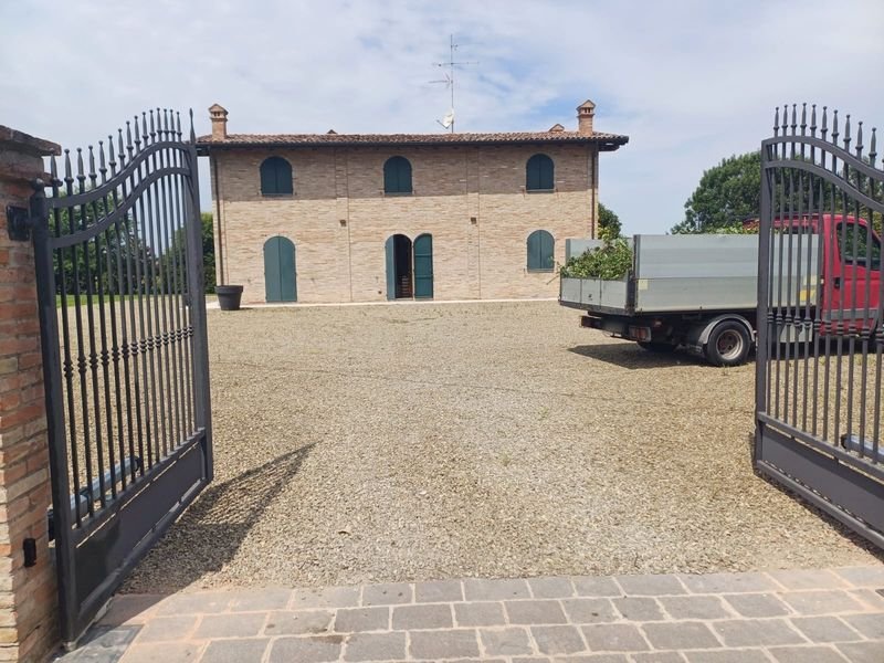 Cancello battente automatico aperto, con il cortile e il casale sullo sfondo