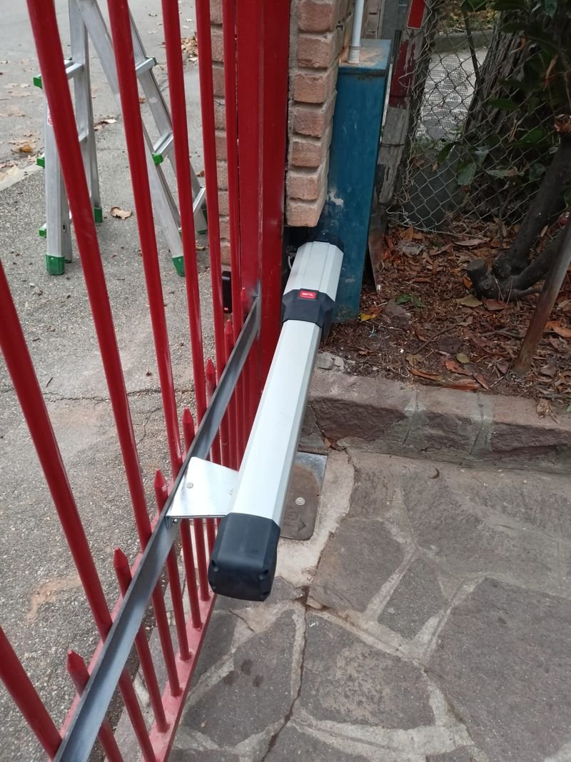 Attuatore lineare fissato con staffa a un cancello rosso a sbarre